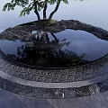 Round Water Fountain Design With Small Island Trees Marble Surroundings And Calm Reflections