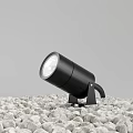 Black Modern Outdoor Spotlight Placed on Gravel Ground with Stable Stand Design