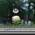 Large Panda Statue In Park With Green Trees And People Walking By