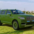 Green Luxury SUV Car With Chrome Grille Large Alloy Wheels On Grass Field City Skyline