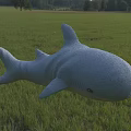 Cute Gray Plush Shark in Green Grass Field with Trees in the Distance