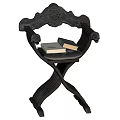 Ornate Black Carved Wooden Stool With Crossed Legs Armrests And Stacked Books On Seat