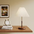Pleated White Shade Table Lamp With Wooden Base Near Alarm Clock And Books On Table