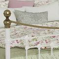 White Iron Bed With Gold Accents Green Quilt Floral Pillows And Bedside Lamp