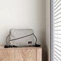 Gray Checkered Crossbody Bag With Black Strap Zipper On Wooden Cabinet By Window Blinds