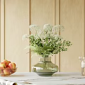 Glass Vase Holding White Flowers And Green Foliage With Apple Bowl And Wooden Wall