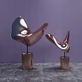 Curved Metallic Sculptures Displayed On Copper Bases Against Purple Background And Marble Surface