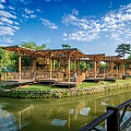 Wooden Pergola Structure Over Pond With Green Trees Grass And Blue Sky