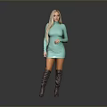 Blonde woman in turquoise dress and gray over-the-knee boots standing against gray background
