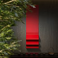 Red Layered Wall Decor On Dark Wooden Wall With Green Foliage Accents