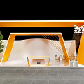Modern Exhibition Booth With Orange Geometric Frame Reception Desk Green Plant And Seating Area