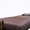 Dark Brown Leather Ottoman with Gray Blanket and Brass Vase in Modern Sleek Design