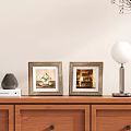 Two Wooden Frames with Floral Art and Interior Scene on Wooden Cabinet with Table Lamp
