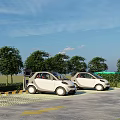Parking Lot With Electric Vehicle Charging Stations And White Cars Near Trees