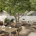 Garden Landscape Design Featuring Outdoor Courtyard Green Trees Wooden Tables Chairs White Walls and Awning