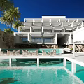 Modern Detached Villa Exterior With Swimming Pool Palm Trees And Lounge Chairs Under Blue Sky