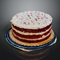 Layered Red Velvet Cake With White Frosting And Red Sprinkles On Plate