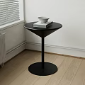 Black Side Table in Corner with White Bowl and Book on Light Wooden Floor