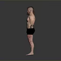 Muscular Shirtless Man in Black Shorts with Arm Wraps Barefoot Standing Against Gray Background