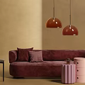 Burgundy Velvet Two-Seater Sofa With Plush Pillows Maroon Pendant Lights And Pink Cylindrical Side Tables