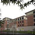 Red Brick School Building With Arched Doors Green Trees And Street Lamps Under Blue Sky