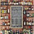 Wine Bottles and Glasses Arranged in Bar with Bricked Wall and Chalkboard Drink Menu