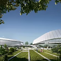 Modern Stadium Building With Curved Roof Glass Facade Green Lawn Trees And Outdoor People