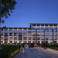 Evening View Of Modern School Building Exterior Illuminated With Trees Lawns And Pedestrians