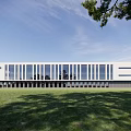 Modern Industrial Factory Building Featuring White Exterior Large Glass Windows Green Grass And Trees