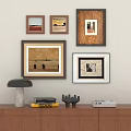 Framed Oil Paintings on Wall Above Wooden Cabinet with Books and Decorative Lamp