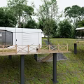 Modern Guesthouse Building With Elevated Wooden Terrace And Lush Green Trees Surrounding
