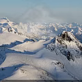 Snowy Mountain Peak With Snow Covered Slopes Rocky Outcrops Under Clear Blue Sky