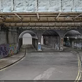 Modern Urban Underpass With Arched Tunnels Graffiti Covered Brick Walls And Paved Road