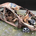 Rusted Damaged Car With Broken Parts And Exposed Interior Abandoned On Grassland