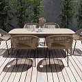 Outdoor Patio Rattan Dining Table And Chairs With Striped Cushions Surrounded By Green Plants