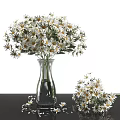Transparent Glass Vase Holding White and Yellow Daisies on Black Tabletop with Small Bouquet Beside
