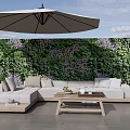 Outdoor Sofa With Wooden Coffee Table And Umbrella Against Greenery Wall With Purple Flowers