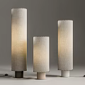 Three Modern Floor Lamps With Cylindrical Fabric Shades And Different Colored Bases