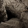 Dimly Lit Cavernous Basement Featuring Stone Stairs Rock Walls And Rope Railings