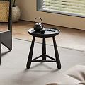 Minimalist Black Round Side Table with Teapot Tray Near Wicker Chair on Herringbone Floor