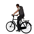A man riding a classic black bicycle in casual style with rear rack