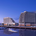 Modern Hotel Buildings Featuring Curved Facades by Marina with Yachts and Water Reflections