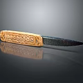 Decorative Knife With Golden Handle Intricate Carvings And Dark Blade On Reflective Surface