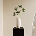 Minimalist White Vase With Green Flowers On Black Stand Against Beige Wall