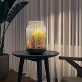 Decorative Ornament Set with Glass Jar Holding Yellow Trees and Orange Details on Small Black Table