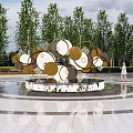 Modern Metal Sculpture With Circular Geometric Shapes In Outdoor Plaza With Fountain And Trees