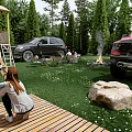 Garden Landscape With Lush Grass Wooden Deck Campfire Area Trees Rock And Parked Vehicles