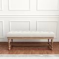 White Tufted Bench with Wooden Legs in Room with White Paneled Walls and Green Plant