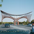 Modern Entrance Gate with Curved Steel Frame Central Logo Surrounded by Trees and Cars