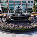 Ornate Circular Fountain With Purple Flower Beds Paved Surroundings And Greenery